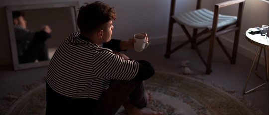Adolescente sentado en el suelo de una habitación.