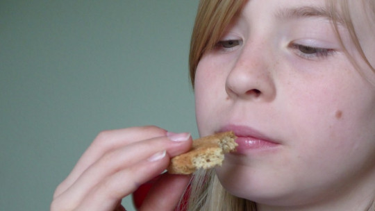 Niña oliendo comida.