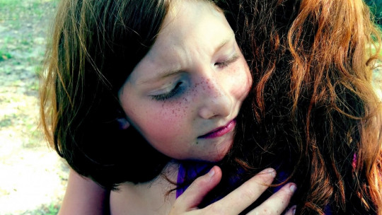 Niña abrazando a mujer.