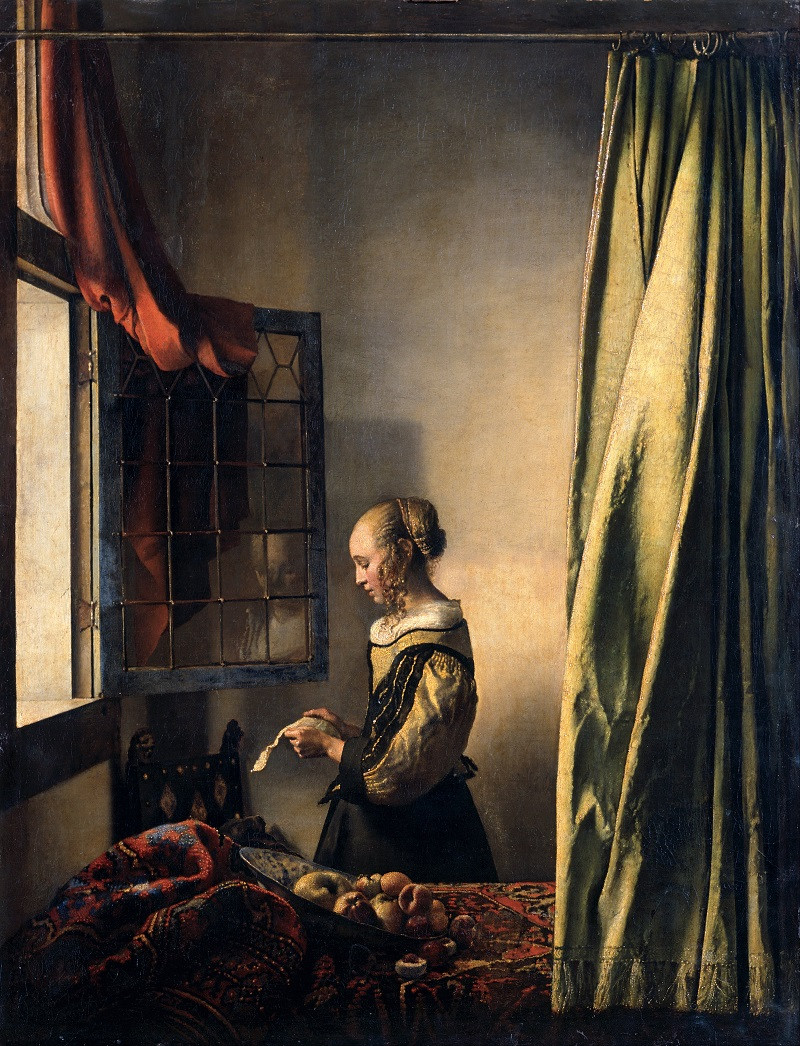 Muchacha leyendo una carta frente a la ventana abierta